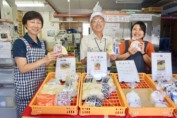 麺を手に持ち店頭に立つ3人